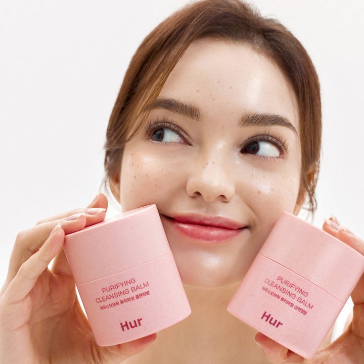 House of Hur Purifying Cleansing Balm 50 ml syväpuhdistava puhdistusbalmi nainen pitelee vaaleanpunaisia purkkeja
