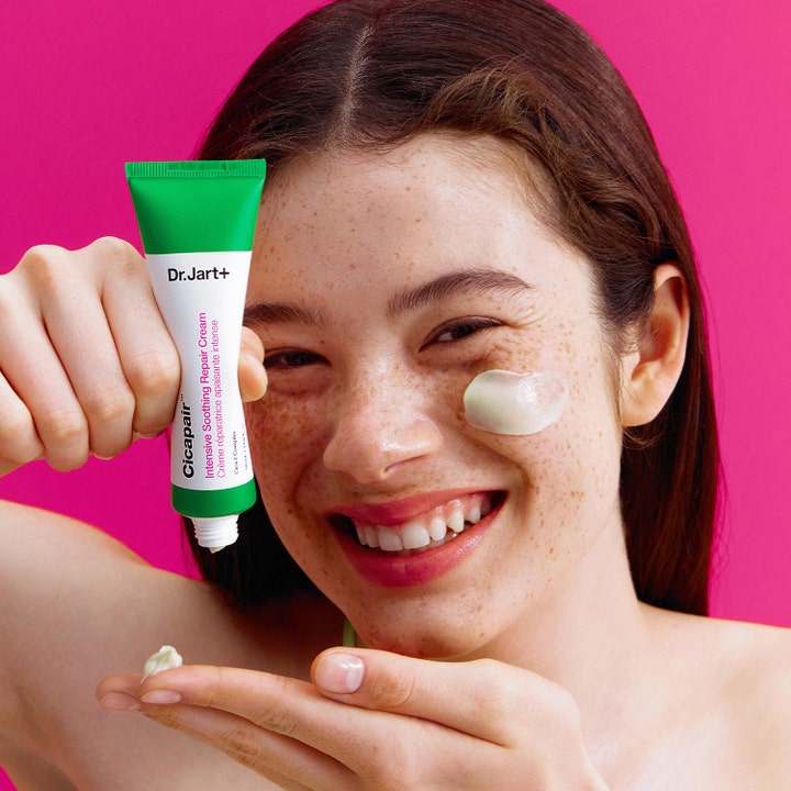 Dr.Jart+ Cicapair Intensive Soothing Repair Cream 50 ml rauhoittava voide tuubissa ja mallin poskella pinkillä taustalla.