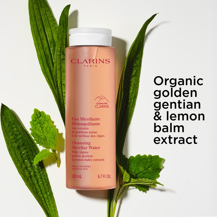 Clarins Cleansing Micellar Water 200 ml puhdistava misellivesi persikkaisessa pullossa vihreiden lehtien ympäröimänä