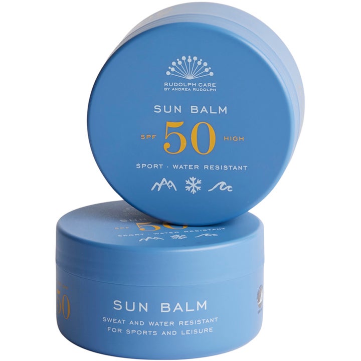 Rudolph Care Sun Balm SPF 50 vedenkestävä aurinkovoide kahdessa sinisessä pyöreässä purkissa keltaisella tekstillä.