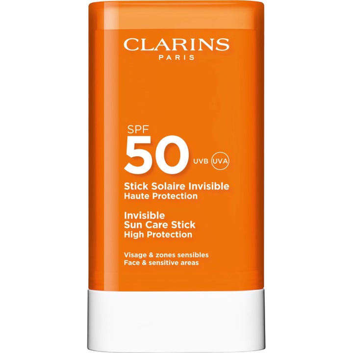 Clarins Invisible Sun Care Stick SPF 50 on suojaava aurinkosuojapuikko oranssissa pakkauksessa valkoisella tyvellä.