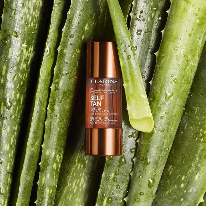 Clarins Golden Glow Booster heleyttävä itseruskettava tiiviste ruskeassa pullossa aloe vera -lehtien välissä.