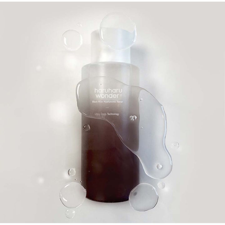 Haruharu wonder Black Rice Hyaluronic Toner 300 ml kosteuttava kasvovesi tummassa pullossa vesipisaroiden keskellä.