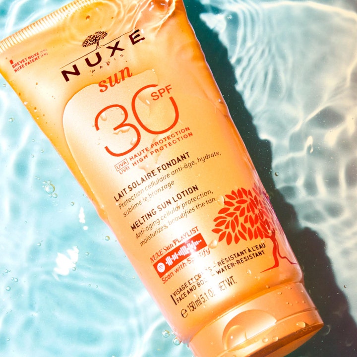 Nuxe Sun Delicious Lotion 150 ml vedenkestävä aurinkovoide SPF 30 oranssissa tuubissa kirkkaassa vedessä.
