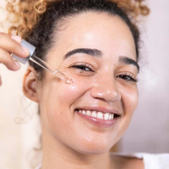Dermalogica AGE Bright Clearing Serum 30 ml kirkastava seerumi levitettynä hymyilevän naisen iholle pipetillä