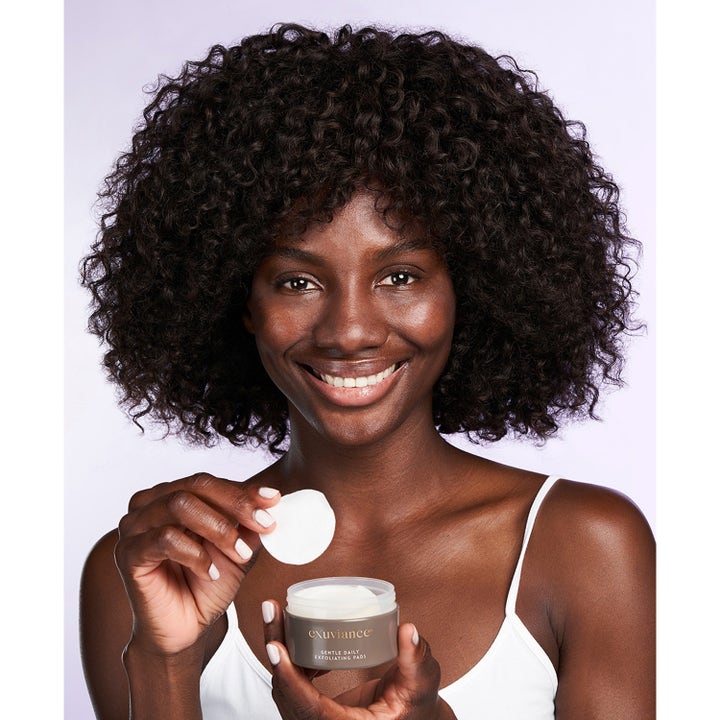 Exuviance Gentle Daily Exfoliating 60 Pads 55 ml kirkastavat kuorintalaput naisen käsissä harmaassa purkissa