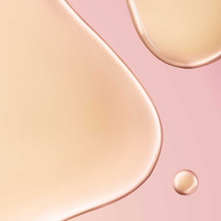 Nuxe Huile Prodigieuse Florale 60 ml vartaloöljy näyttää koostumuksen pehmeät ja kultaiset pisarat vaaleanpunaisella taustalla.