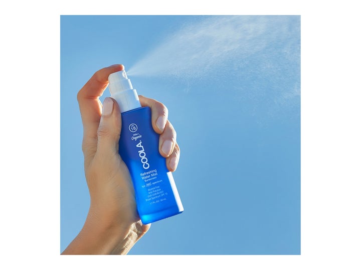 COOLA Refreshing Water Mist SPF15 50 ml kosteuttava kasvosuihke sinisessä pullossa jota suihkutetaan taivasta vasten.