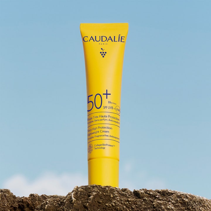 Caudalie Vinosun Lightweight Fluid SPF50 40 ml aurinkovoide kasvoille keltaisessa tuubissa kalliolla.