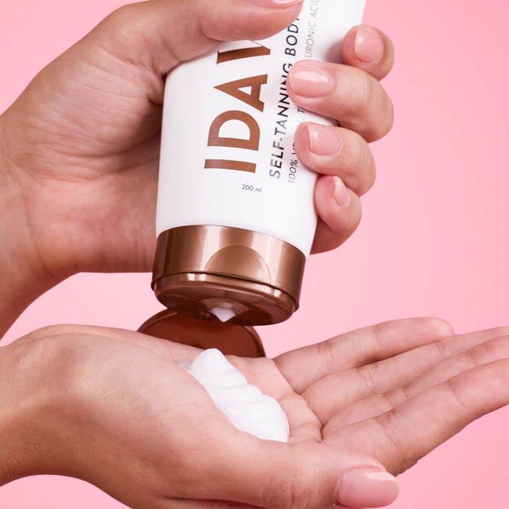 IDA WARG Beauty Self Tanning Body Lotion 200 ml itseruskettava voide puristetaan kämmenelle vaaleanpunaisella taustalla