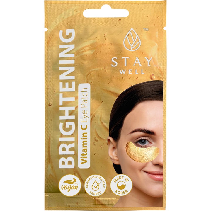 Stay Well Brightening Vitamin C Eye Patch kirkastavat silmälaput kultaisessa pussissa, jossa nainen käyttää kultaista lappua.