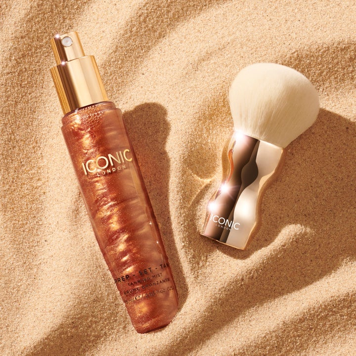 ICONIC London Prep Set Tan Tanning Mist Glow 75 ml hehkua antava itseruskettava suihke ja sivellin hiekalla.