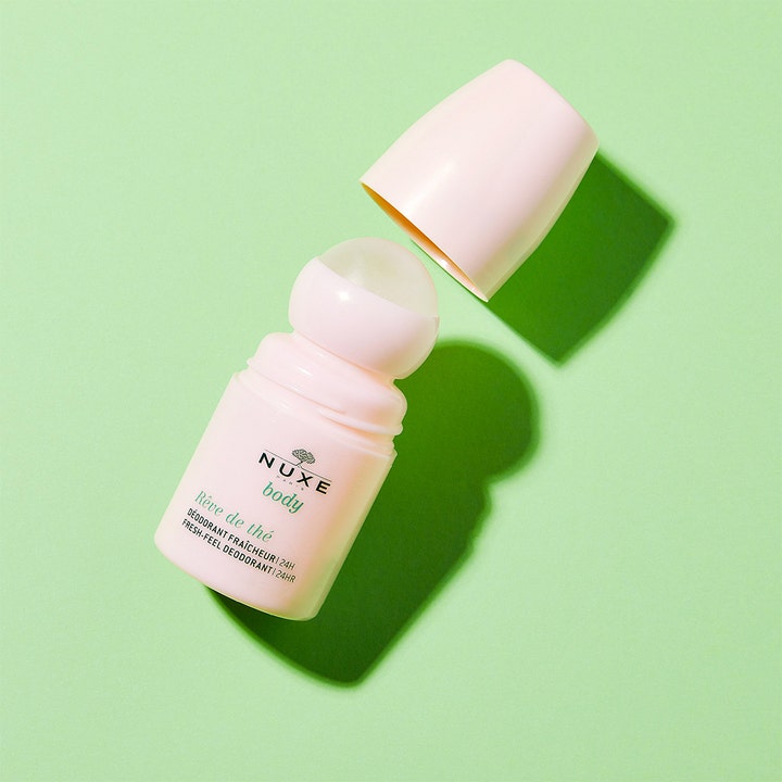 Nuxe Body Reve De Thé Fresh Deodorant 50 ml antaa 24h raikkauden vaaleanpunaisessa roll-on-pullossa avatulla korkilla.