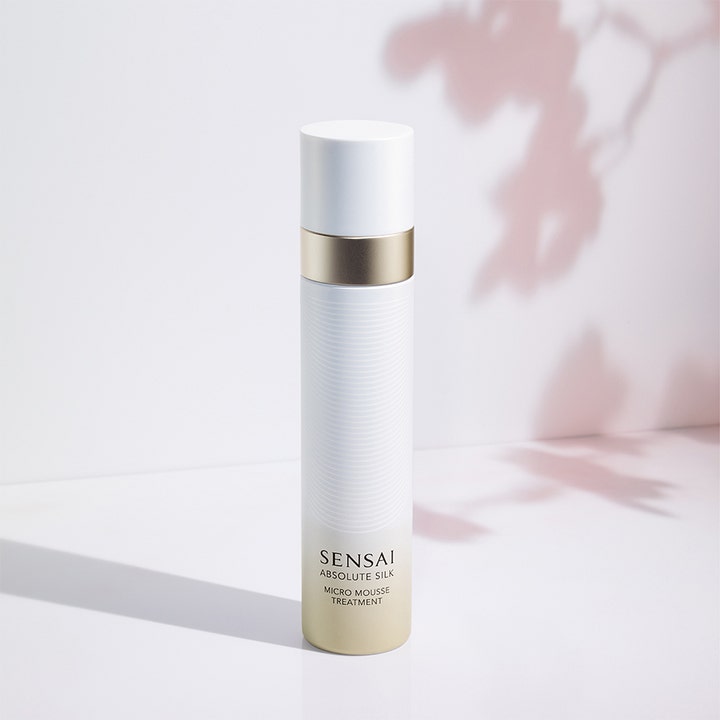 Sensai Absolute Silk Micro Mousse Treatment 90 ml kasvovesi on valkoisessa pullossa, jossa on kultaisia yksityiskohtia.