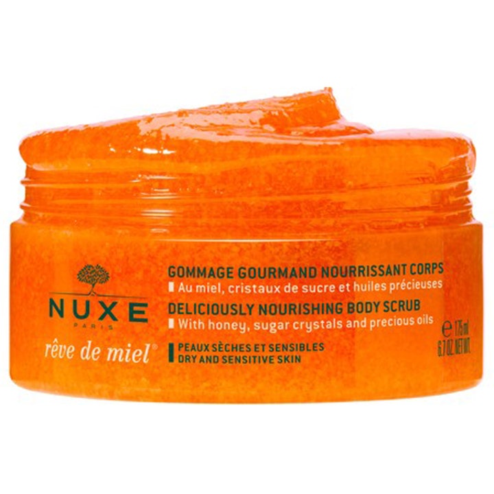 Nuxe Rêve de Miel 175 ml ravitseva vartalokuorinta avatussa oranssissa purkissa, jossa on täyteläinen sokerikoostumus.