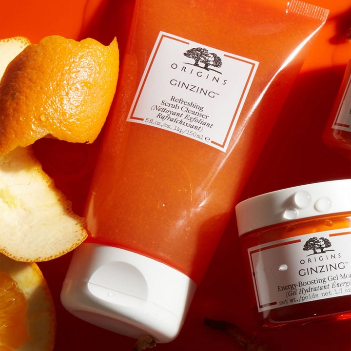 Origins GinZing Refreshing Scrub Cleanser 150 ml kirkastava kuorinta oranssissa tuubissa appelsiininkuorten rinnalla
