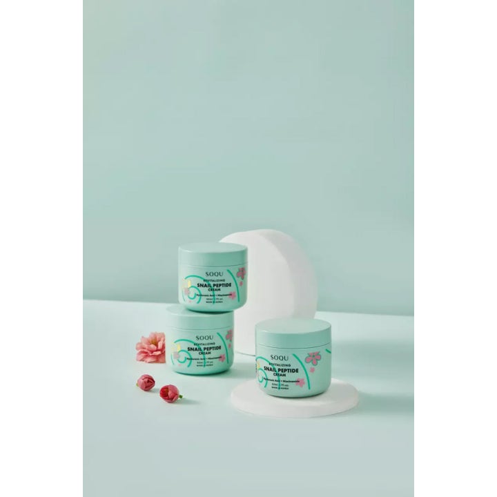 SOQU Snail Peptide Cream 50 ml elvyttävä kasvovoide kolmessa vaaleansinisessä purkissa kukkien ja koristeiden kera.
