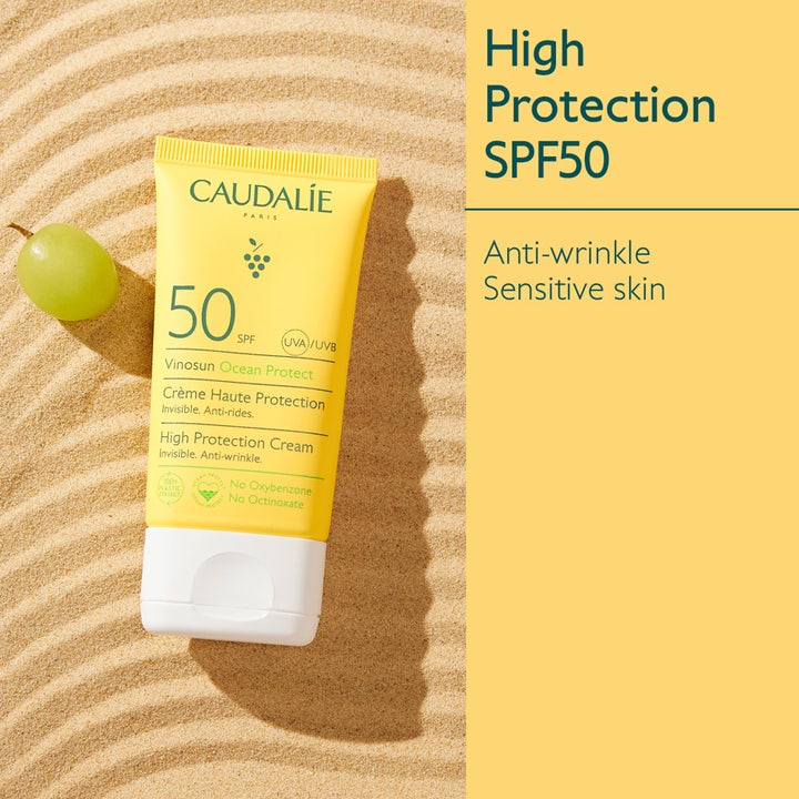 Caudalie Vinosun Protect Cream SPF50+ 50 ml aurinkovoide kasvoille keltaisessa tuubissa hiekalla viinirypäleen kera.