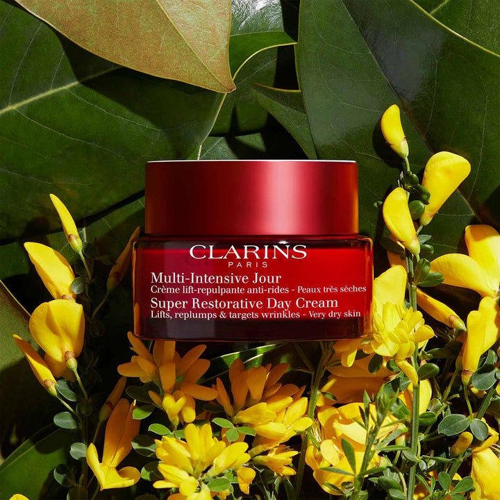 Clarins Super Restorative Day Cream 50 ml elvyttävä päivävoide punaisessa purkissa keltaisten kukkien keskellä