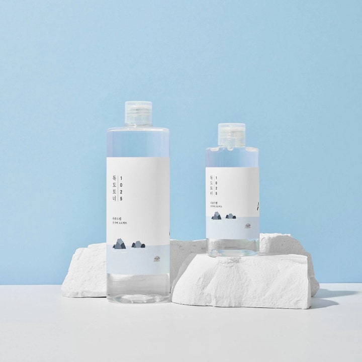 Round Lab 1025 Dokdo Toner 500 ml kosteuttava kasvovesi kirkkaissa pulloissa valkoisten kivien päällä sinisellä taustalla.