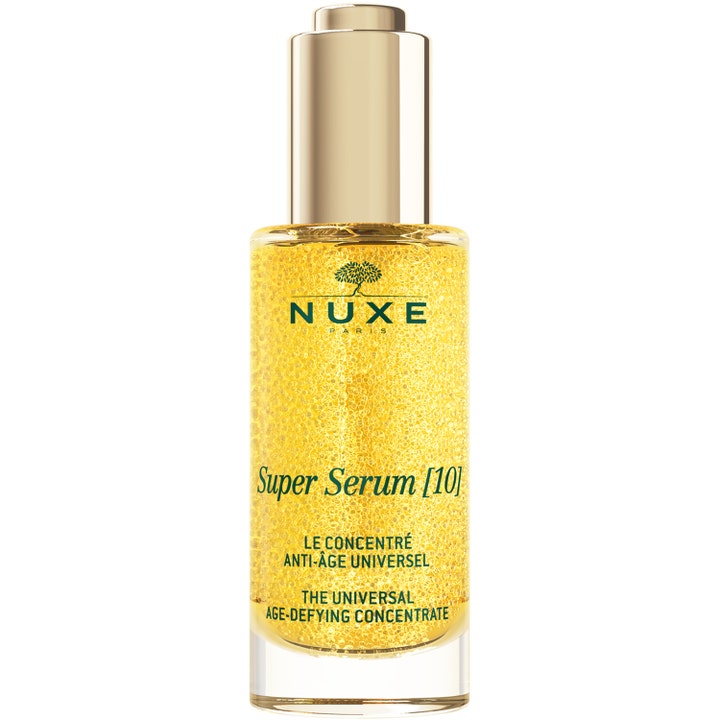 Nuxe Super Serum [10] 30 ml silottava anti-age-seerumi sisältää kultaisia öljyhelmiä kirkkaassa lasipullossa.