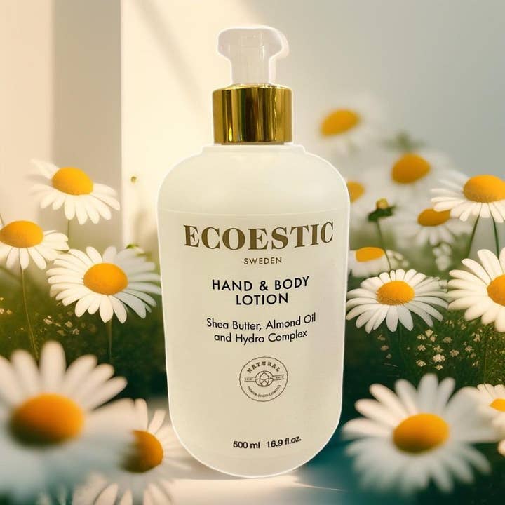 ECOESTIC Hand & Body Lotion 500 ml kosteuttava vartalovoide valkoisessa pumppupullossa kukkien keskellä.