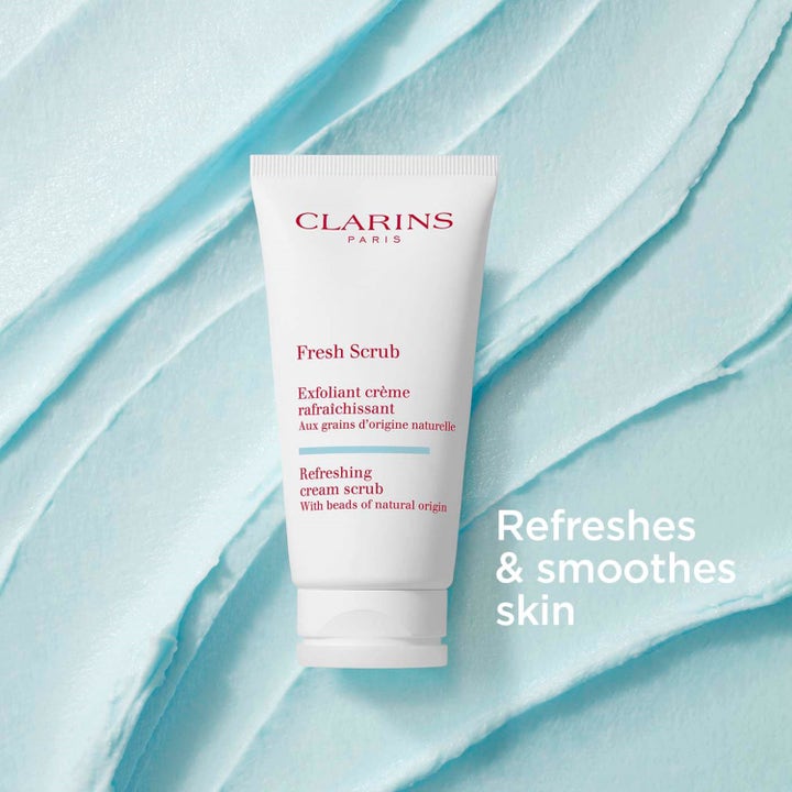 Clarins Fresh Scrub 50 ml virkistävä kasvokuorinta valkoisessa tuubissa vaaleansinisen voidemaisen tekstuurin päällä.