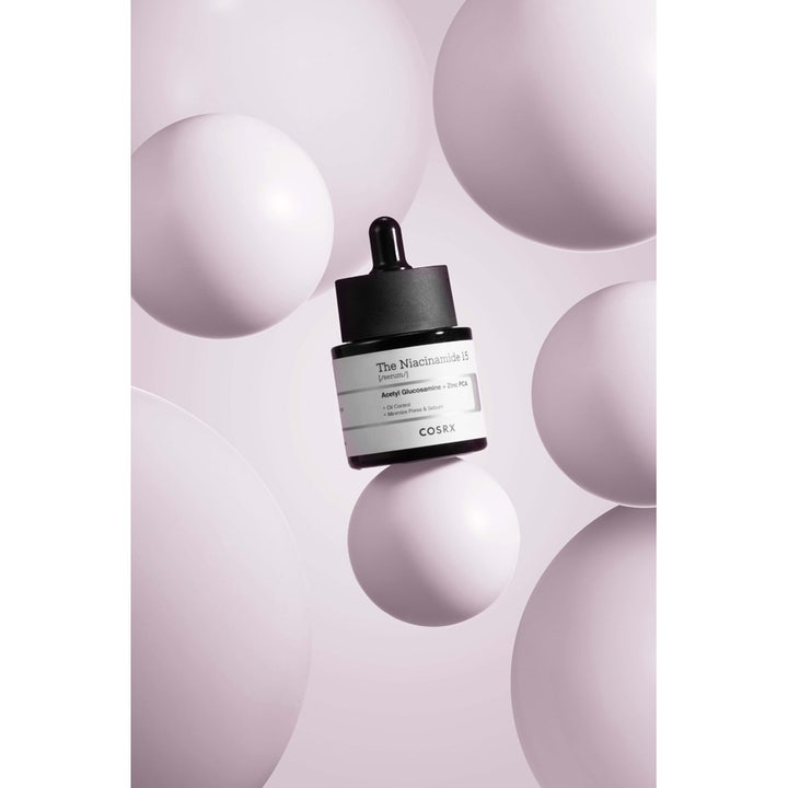 COSRX The Niacinamide 15 Serum 20 ml talia säätelevä kasvoseerumi tummassa pipettipullossa liilojen pallojen keskellä