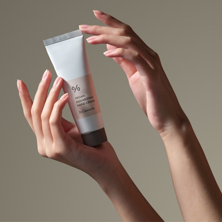 Dr. Ceuracle Vegan Aquarizing Hand Cream 50 ml kosteuttava käsivoide käsien pitelemässä vaaleassa tuubissa.