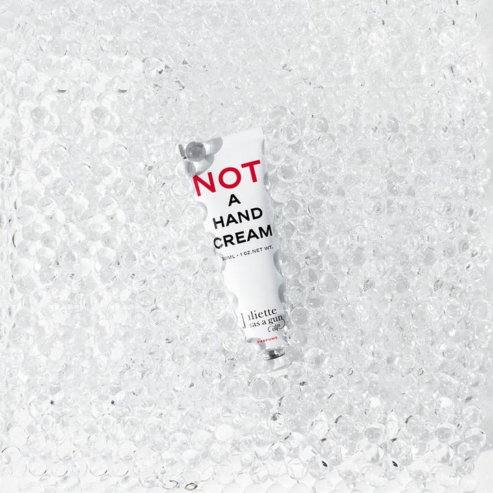 Juliette has a gun Not A Perfume Hand Cream 30 ml käsivoide valkoisessa tuubissa kirkkaiden lasikuulien päällä.