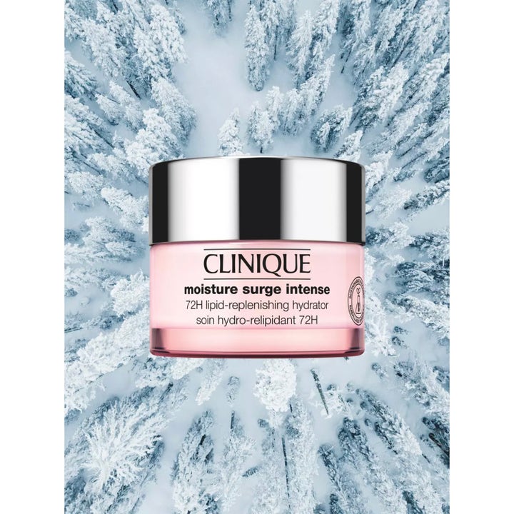 Clinique Moisture Surge Intense 72H 125 ml kosteuttava kasvovoide vaaleanpunaisessa purkissa lumisen metsän yllä.