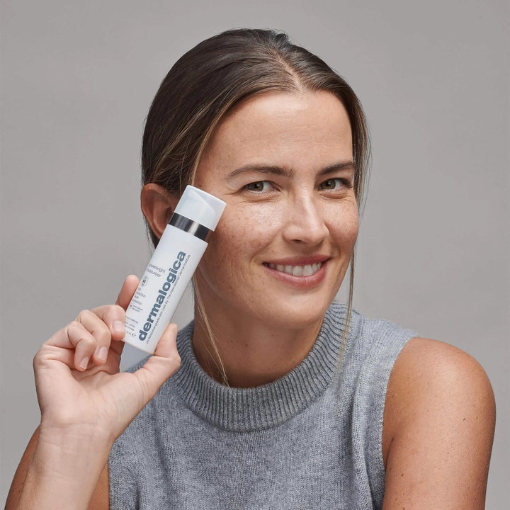 Dermalogica Powerbright Moisturizer SPF50 50 ml kirkastava päivävoide jota hymyilevä nainen pitelee.