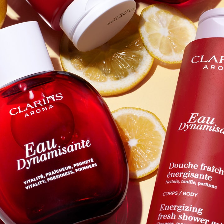 Clarins Eau Dynamisante 200 ml virkistävä suihkugeeli punaisessa tuubissa ja pullossa sitruunaviipaleiden kera.
