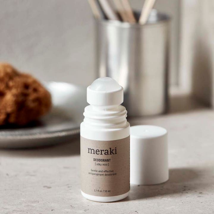 Meraki Deodorant Silky Mist 50 ml antiperspirantti valkoisessa roll-on-pullossa, jossa on beige etiketti ja avattu korkki.
