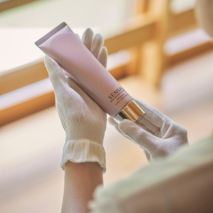 Sensai Cellular Performance Intensive Hand Treatment 100 ml pehmentävä käsivoide valkoisissa puuvillahansikkaissa.