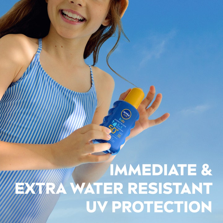 NIVEA Sun Protect & Care Kids Spray 200 ml SPF50+ aurinkosuojasuihku tytön käsissä sinistä taivasta vasten.