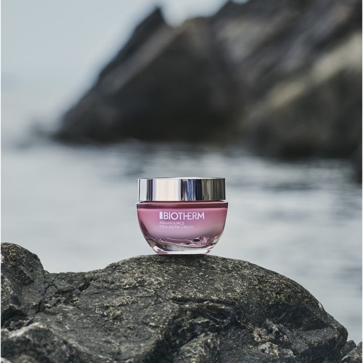 Biotherm Aquasource Cica Nutri 30 ml kosteuttava päivävoide vaaleanpunaisessa purkissa kalliolla meren rannalla.