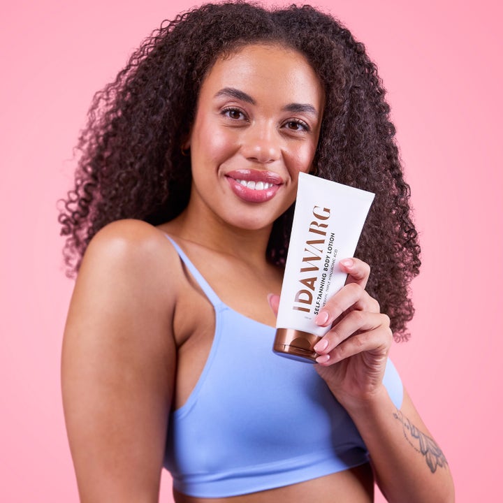 IDA WARG Beauty Self Tanning Body Lotion 200 ml itseruskettava vartalovoide jota nainen pitelee pinkkiä taustaa vasten