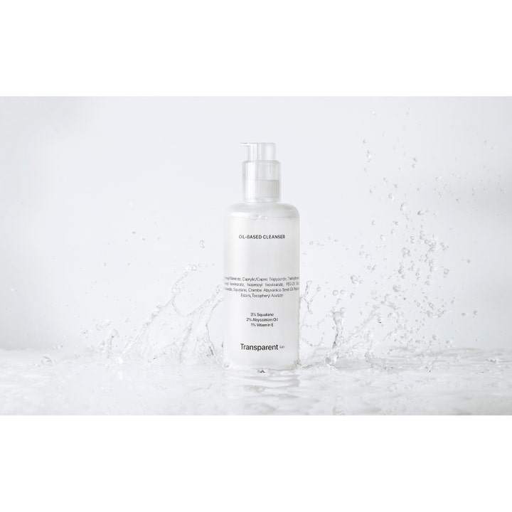Transparent Lab Oil-Based Cleanser 200 ml puhdistusöljy skvalaanilla valkoisessa pullossa vesiroiskeiden keskellä.