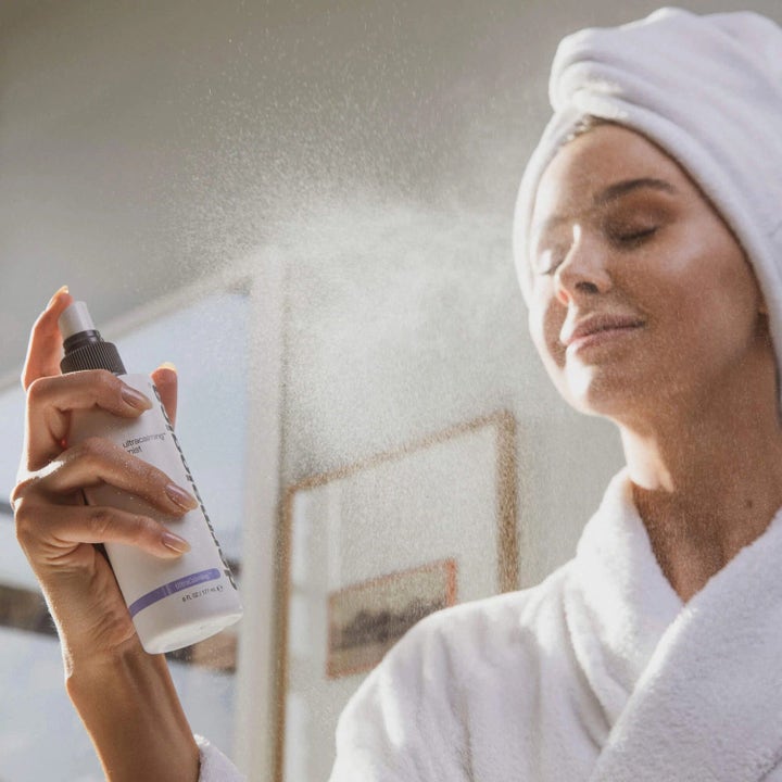 Dermalogica UltraCalming Mist Duo rauhoittava kasvosuihke, jota nainen suihkuttaa iholleen kylpytakissa.