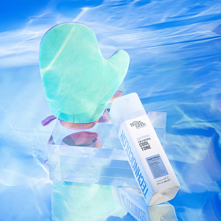 Bondi Sands Technocolor Sapphire 200 ml itseruskettava vaahto ja vaaleanvihreä levityskinnas veden heijastuksissa.