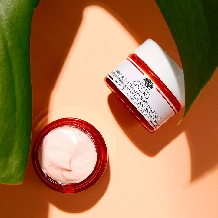 Origins GinZing Brightening Eye Cream Cool Shade 15 ml kirkastava silmänympärysvoide ja vaaleanpunainen voidekoostumus.