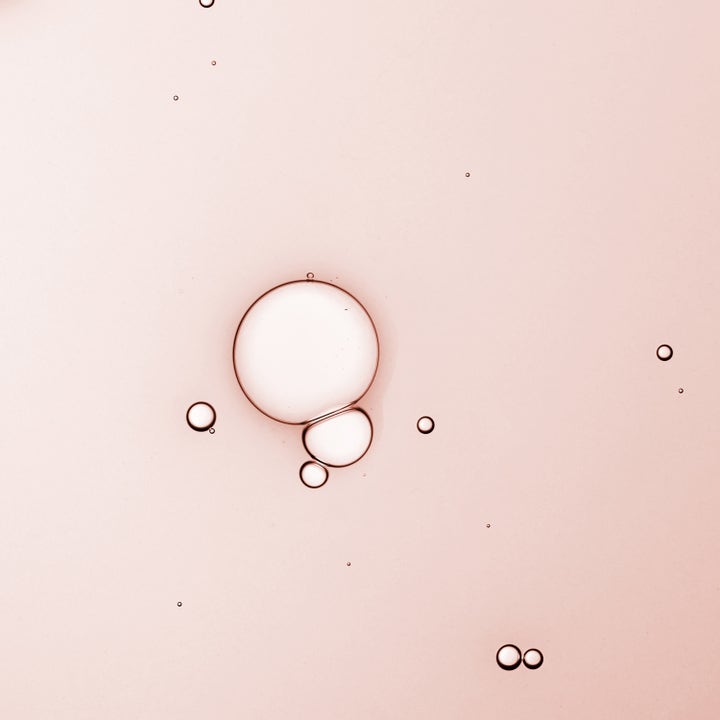 KORA Organics Turmeric Glow Drops 30 ml heleyttävä seerumi, jonka vaaleanpunaisessa tekstuurissa on öljypisaroita.