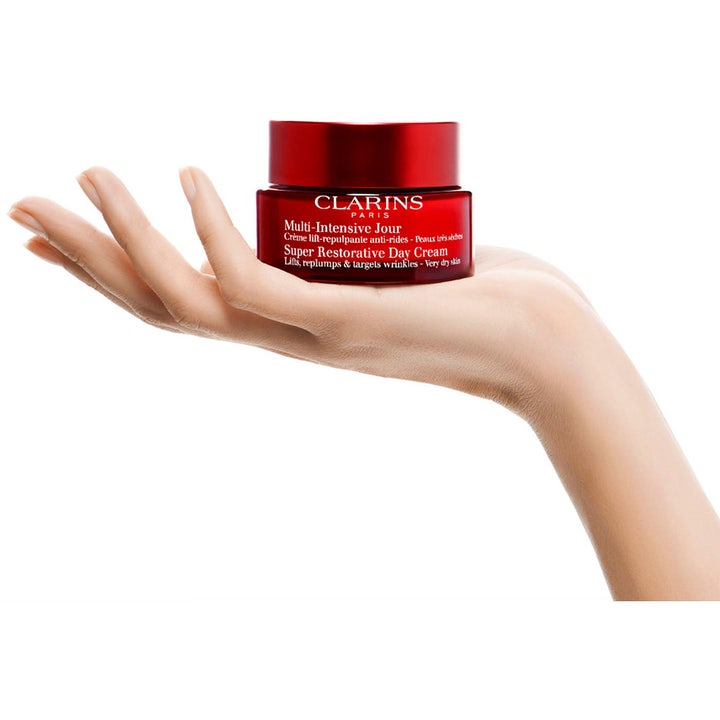 Clarins Super Restorative Day Cream 50 ml silottava päivävoide punaisessa purkissa kämmenellä.