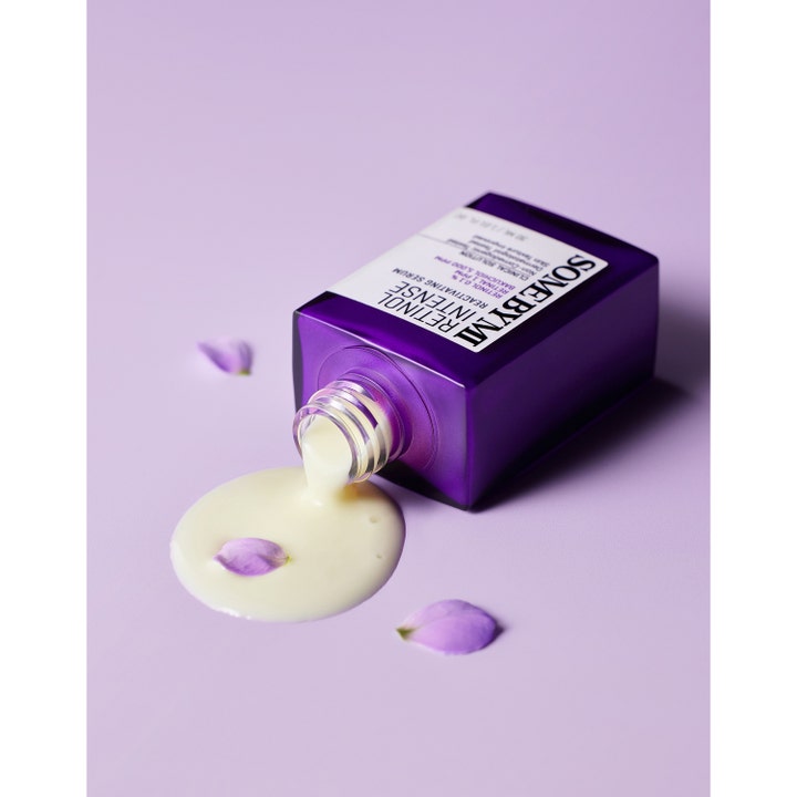 Some By Mi Retinol Intense Reactivating Serum 30 ml kermainen seerumi valuu violetista pullosta liiloille terälehdille.