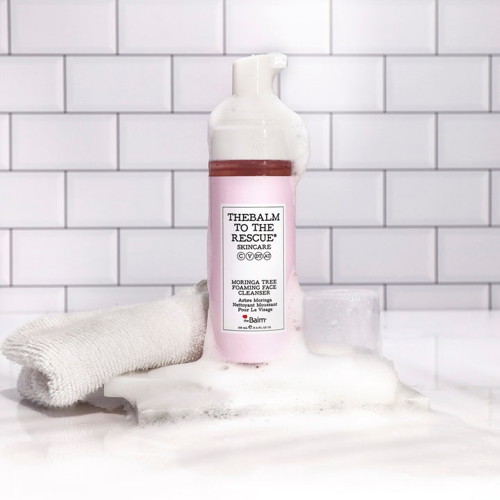 theBalm theBalm to the Rescue 150 ml puhdistusvaahto moringalla vaaleanpunaisessa pullossa valkoisen vaahdon ympäröimänä.