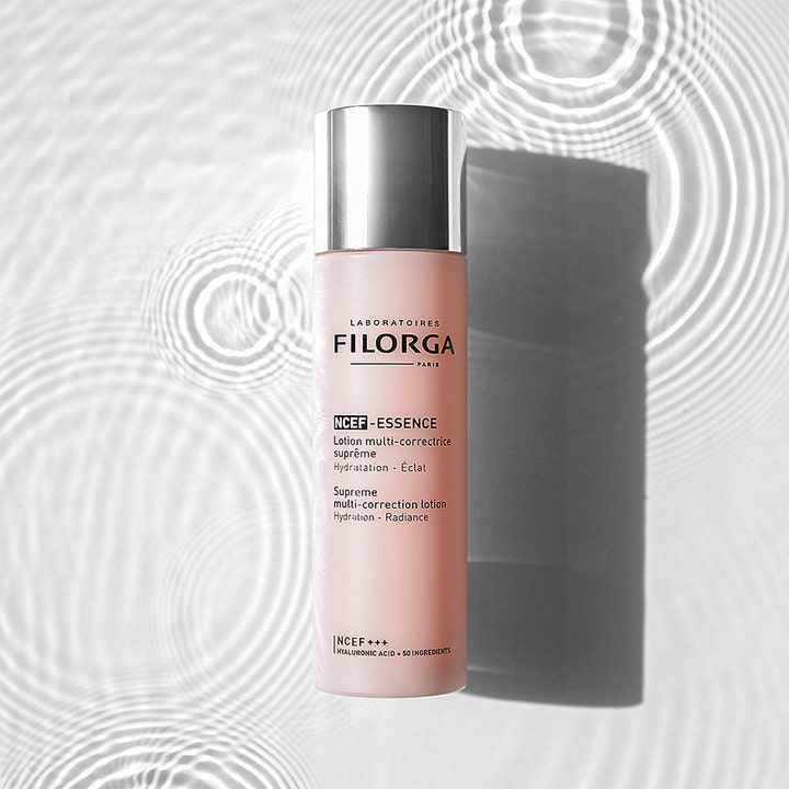 Filorga NCEF-Essence Supreme Multi-correction Lotion 150 ml heleyttävä hoitoneste vaaleanpunaisessa pullossa veden päällä