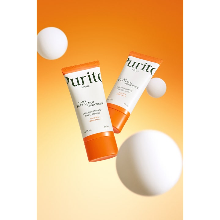 Purito Daily Soft Touch Sunscreen 60 ml SPF 50+ aurinkovoide kasvoille suojaavilla keramideilla oranssilla taustalla.