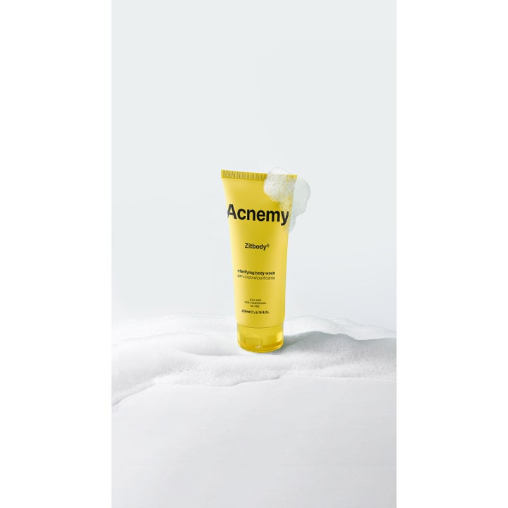 Niche Beauty Lab Acnemy Zitbody 200 ml puhdistava suihkugeeli vartalolle keltaisessa tuubissa keskellä valkoista vaahtoa