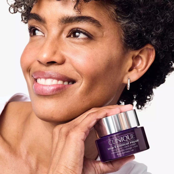 Clinique Smart Clinical Repair Lifting Face + Neck Cream 75 ml kiinteyttävä kasvovoide hymyilevän naisen pitelemänä